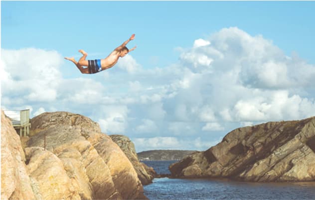 Mensch springt ins Wasser mit hügeliger Landschaft im Hintergrund